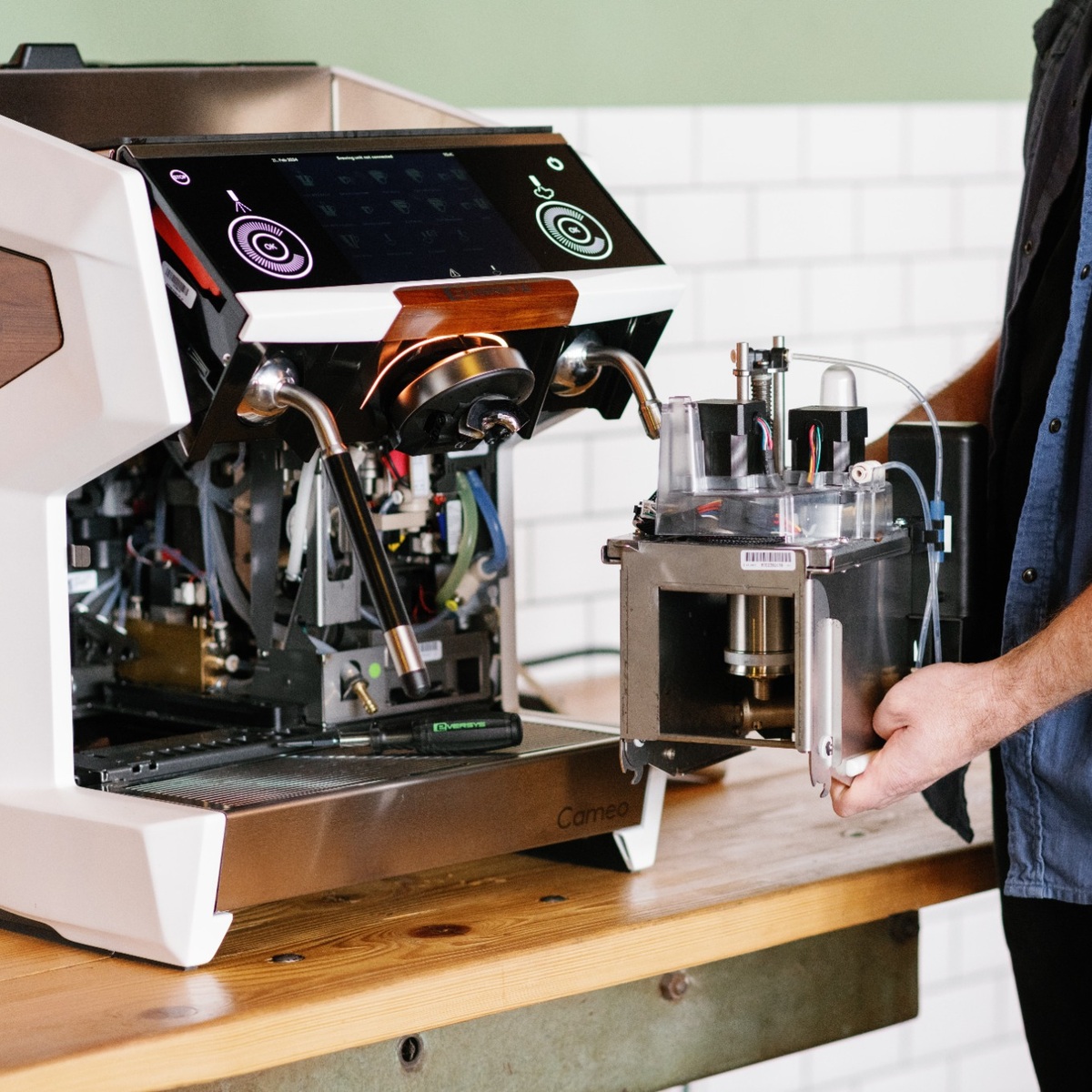 Techniker bei der Wartung einer geöffneten Eversys Cameo Kaffeemaschine mit ausgebauter Brühgruppe